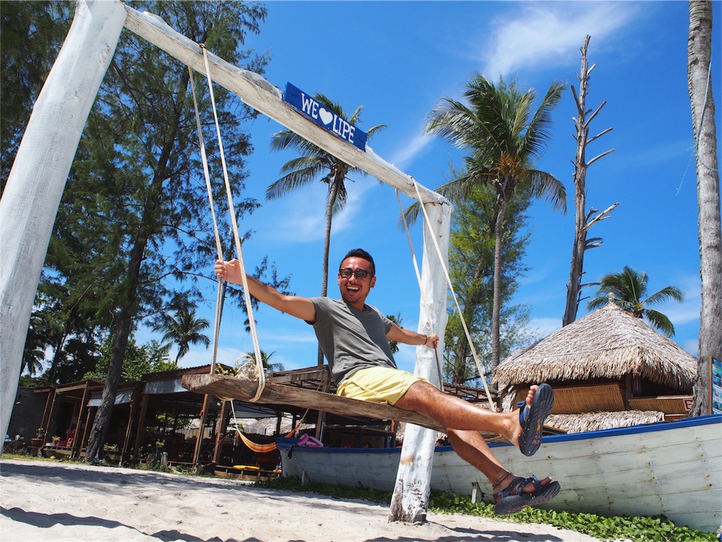 海を目の前にブランコではしゃぐ旦那さん