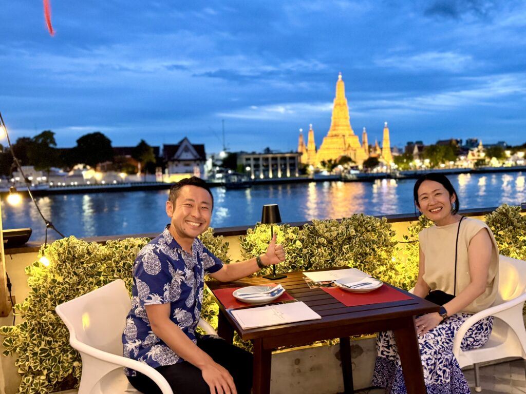 Chom Arun（チョムアルン）のルーフトップからの見る夕景でライトアップされたワットアルンと記念撮影